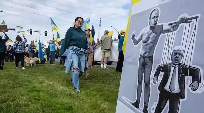美俄峰会在即，美国阿拉斯加民众手举乌克兰国旗坚定支持乌克兰，树起巨幅海报嘲讽特朗