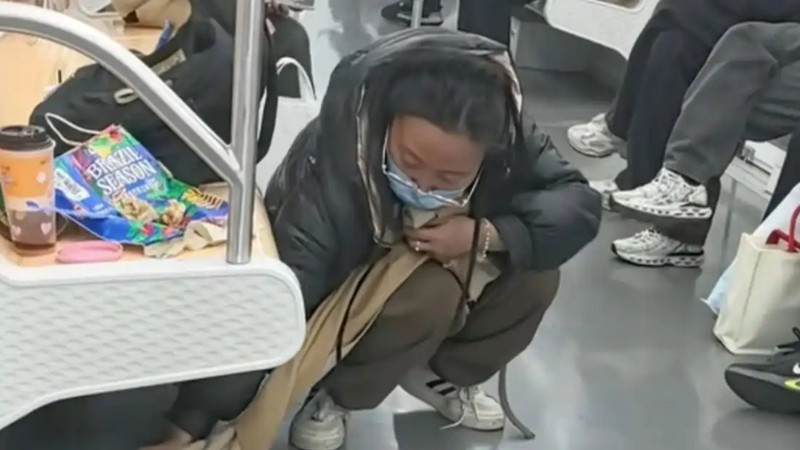 女子拿围巾擦拭洒在地铁上的饮料，着实难得