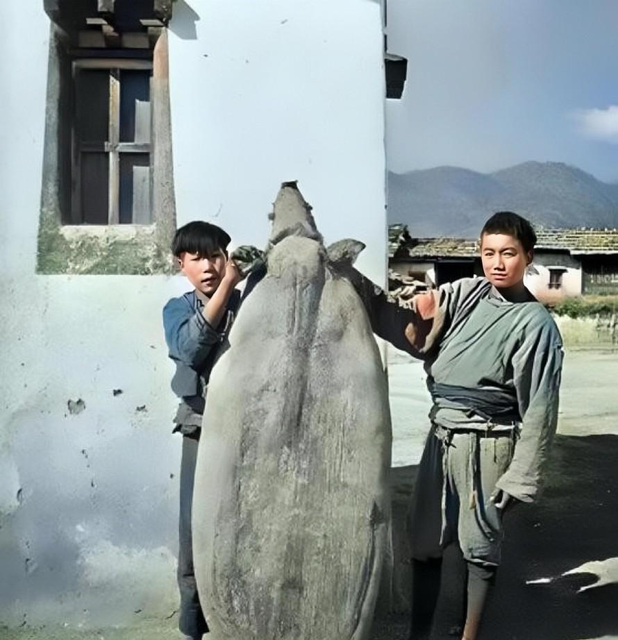 民国时期，云南，两名摩梭族小伙正在展示特色“猪膘肉”，这是一头整猪宰杀，去除内脏