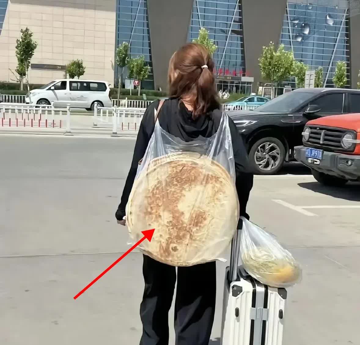 在深圳火车站，一名男子撞见个特别的场景：一个女子推着行李箱，背上竟驮着俩宽度近4