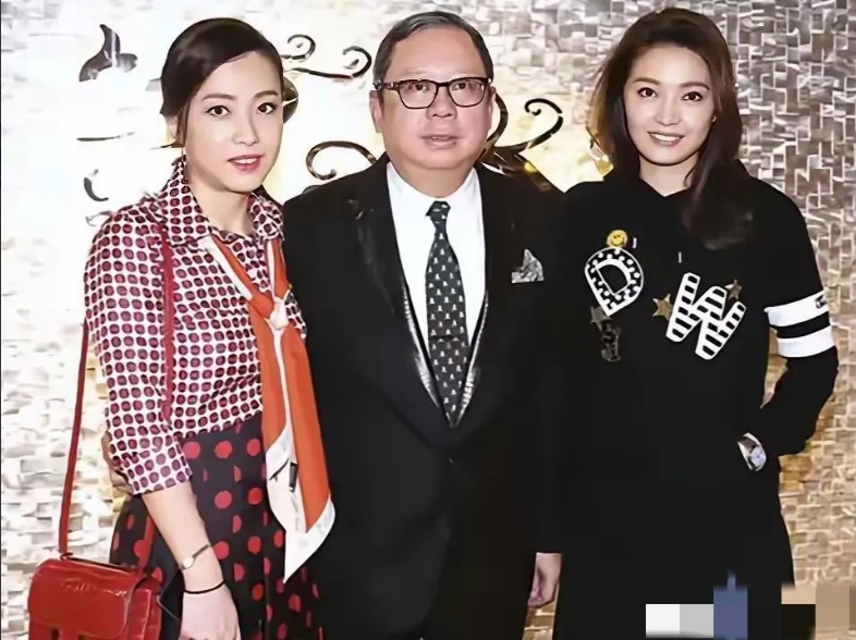 画面中西装革履的大佬林建岳体型偏胖，个头偏矮；右侧的甘比明眸皓齿，珠光玉色；左侧