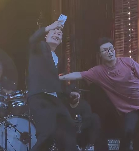 汪峰正在台上准备开口唱歌，一位男粉丝突然举着手机冲上来，要求合影，完全没有注意到