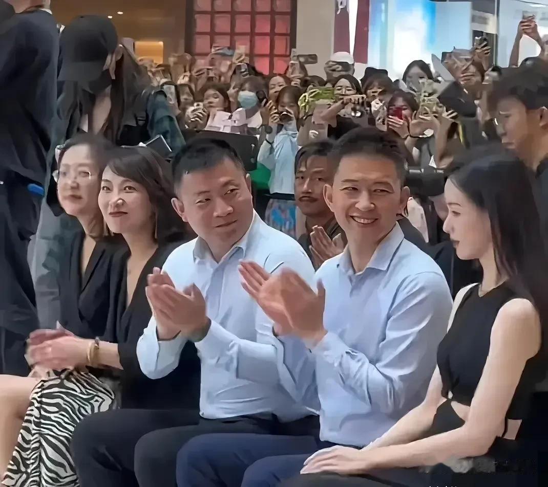 照片中这个女明星的魅力挺大的，旁边两个穿衬衣拍手的男人都侧着脸看她。 
看样子上