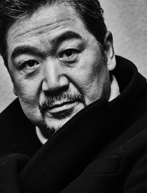 张国立穿黑色大衣，手拿雪茄，眼神时而深沉，时而充满笑意，非常有范儿