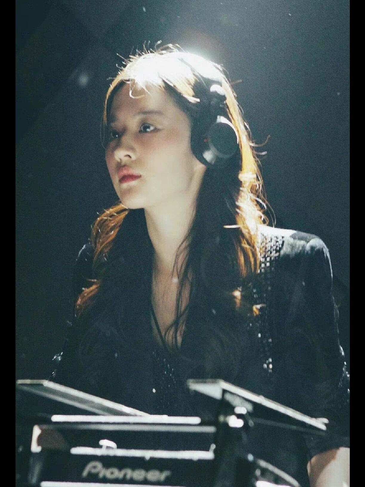 刘亦菲头戴耳机，表情看起来很专注和投入，仿佛正在全神贯注地演唱。