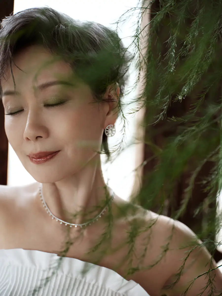 叶童一袭白色西装知性贵气，侧颜倚坐尽显从容优雅
