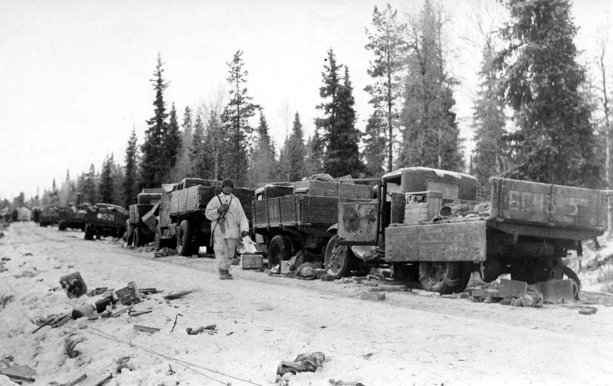1940 年 1 月，一名芬兰士兵走过被击毁的苏联军车。