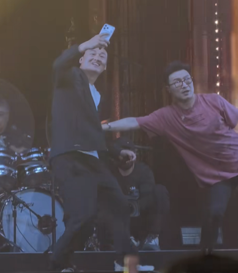 汪峰正在台上准备开口唱歌，一位男粉丝突然举着手机冲上来，要求合影，完全没有注意到