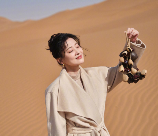 梅婷分享了一组很有寓意的照片沙漠里的春天
她身穿米色大衣，背景为沙漠与湛蓝的湖水