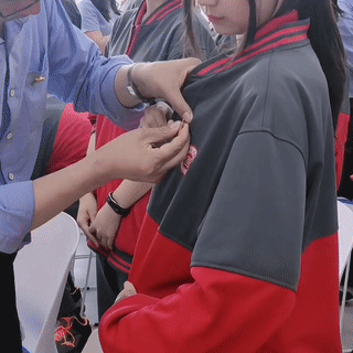 男老师手伸入,女学生衣领内,帮带戴胸章,引热议