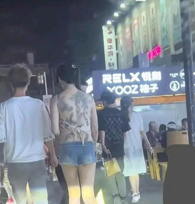 纪实：女子穿着一块布逛夜市，露出满背纹身惹争议，男友贴心搂腰