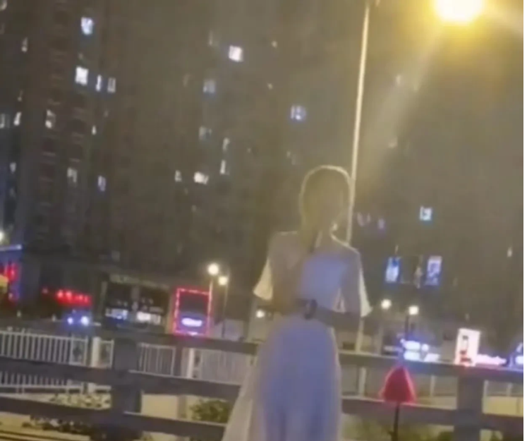 山西太原,一名男子居然穿着一件白色连衣裙,在居民区旁边的天桥上直播