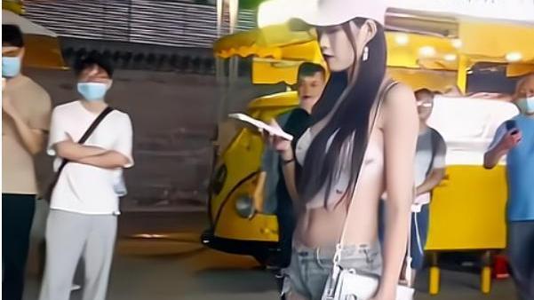 纪实：女子穿着清凉，身上纹身清晰可见，路旁十余名男子停下拍照