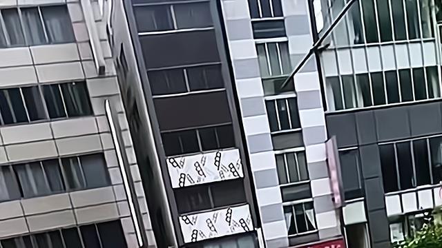 一女子在路边的花坛前拍照，不慎滑了一下，后仰摔进花坛