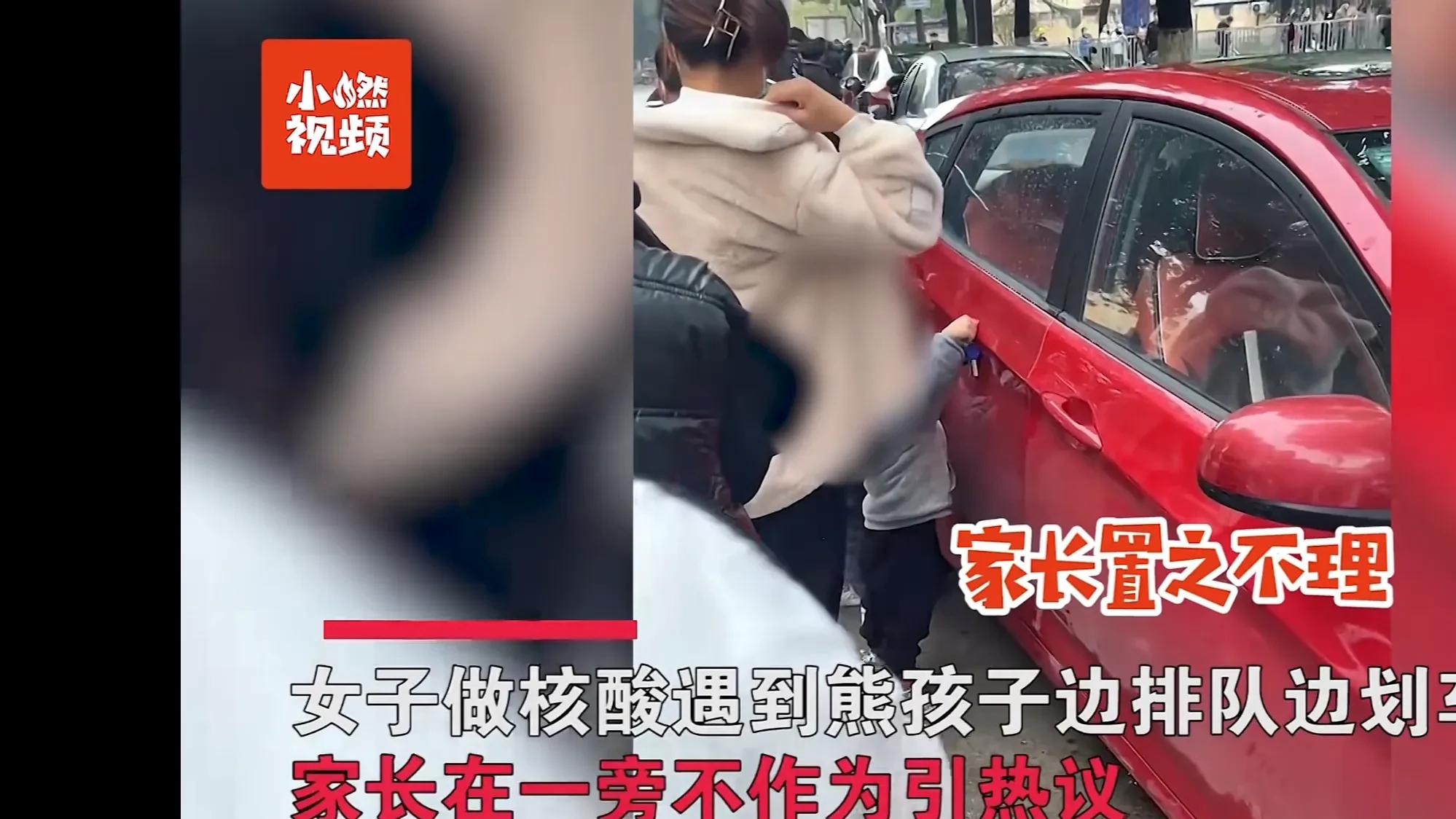 江苏常州，一名年轻女子带着两个小孩做核酸，对着路边的车子划来划去却视而不见