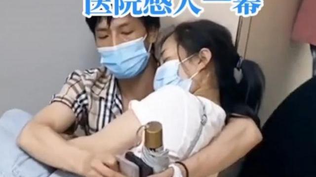 医院里，一男子靠墙蹲着，把生病的妻子横抱在怀里