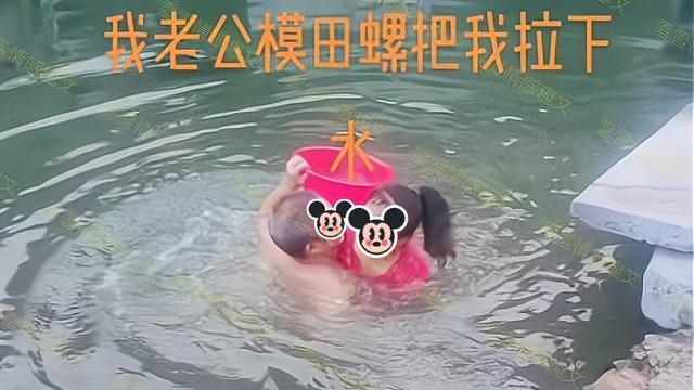男子在水塘里摸田螺，妻子在岸上观看，他趁妻子不备把她拉下水