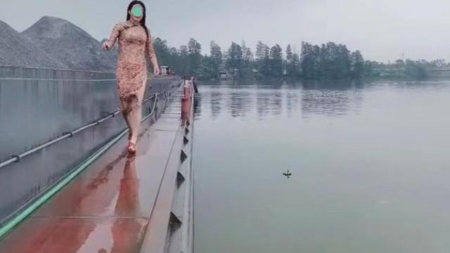 一位身穿旗袍的女子，跑到小河边，连鞋都没脱就往河里跳