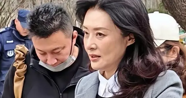 58岁周涛在北京朗园游玩，穿长筒靴和灰大衣，一头长卷发气质非凡