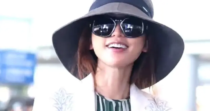 50岁林志玲机场路透，白色西服外套搭配条纹长裙，女神优雅自如