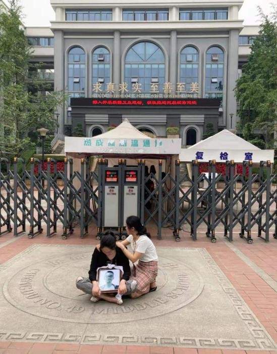 時間要聞 成都墜亡學生家長抱著遺像坐在學校門口，背后就是校訓：求真求實