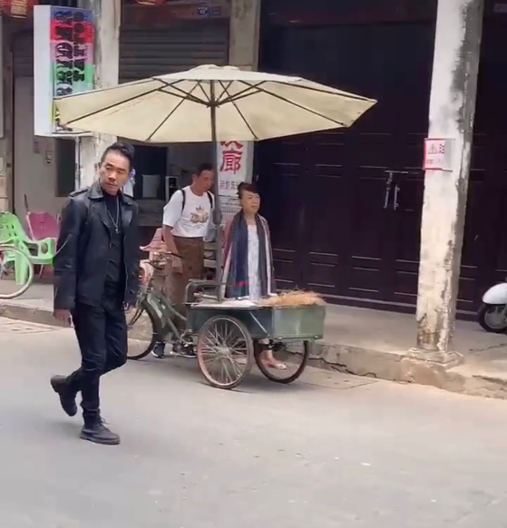 陈小春|陈小春在海南拍戏，大热天还穿着皮衣，寥寥几个路人坐电动车观望