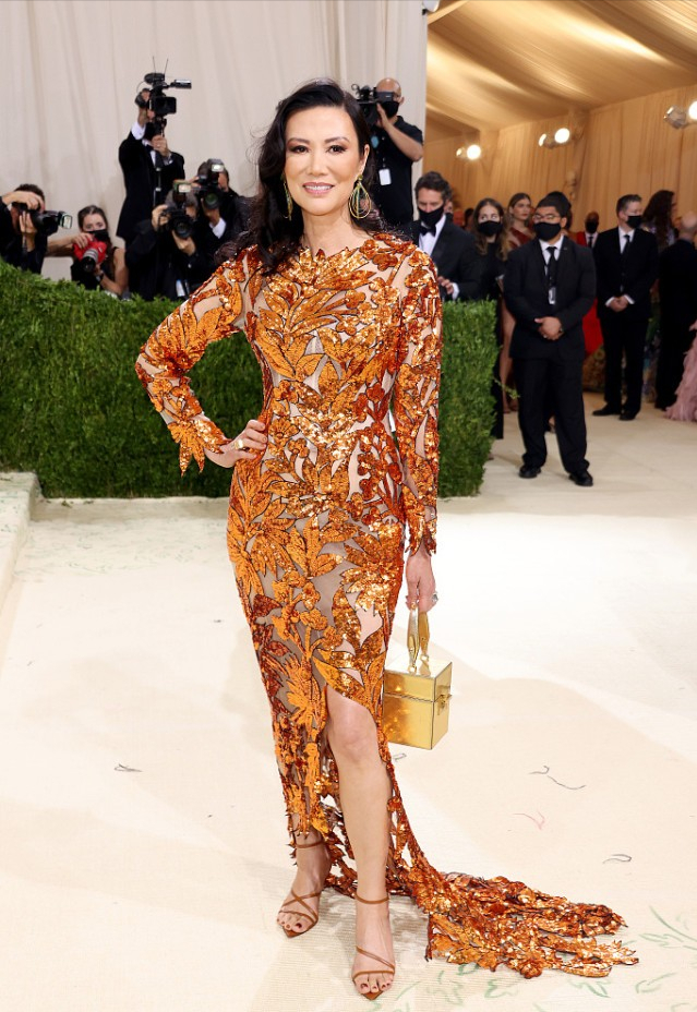 邓文迪 54岁的邓文迪化紫色眼妆媚而不妖，穿橘色花纹裙，衬得很高贵