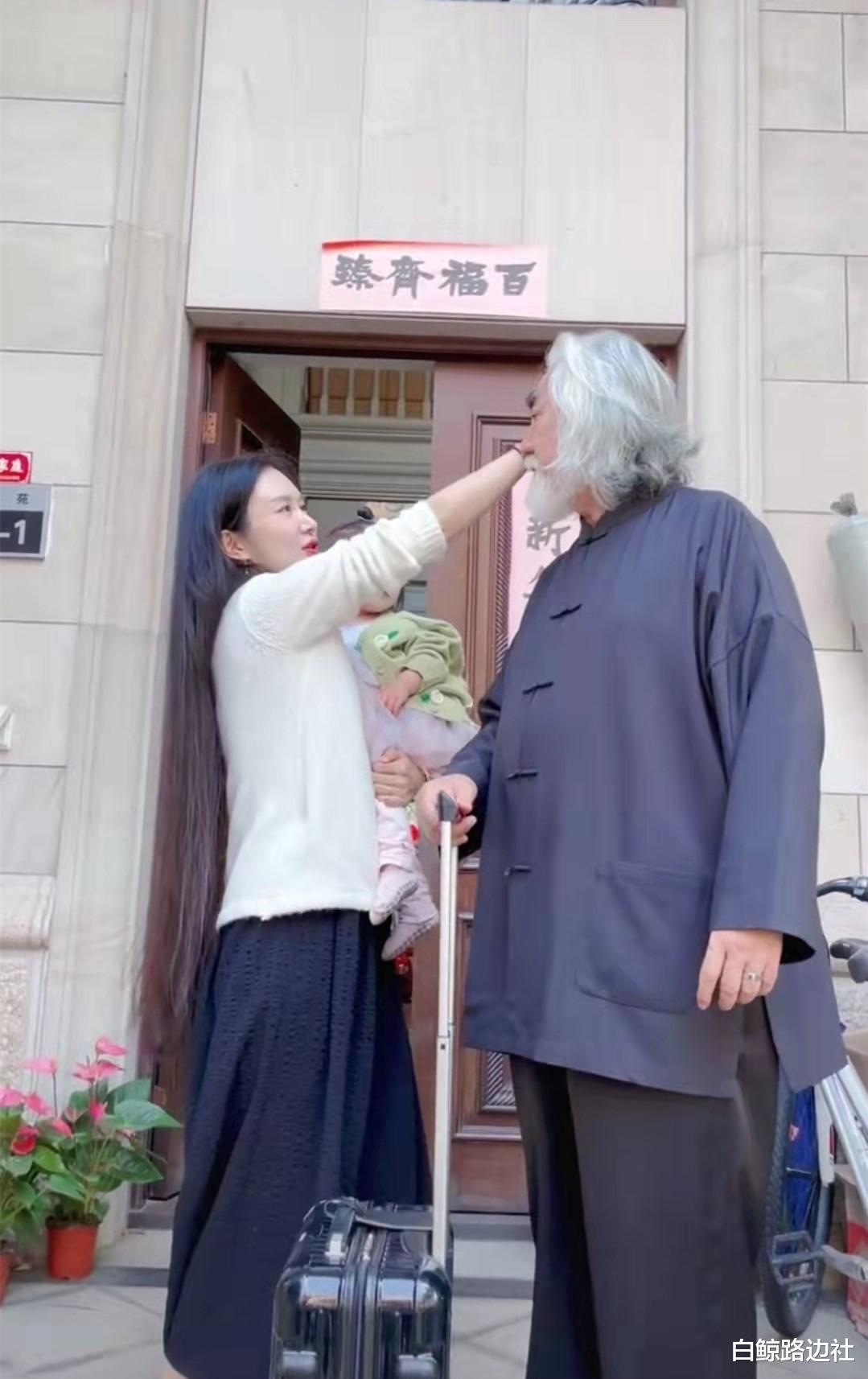 张纪中|70岁张纪中拎行李箱出差！小31岁妻子抱女儿送行，家门惜别遭吐槽