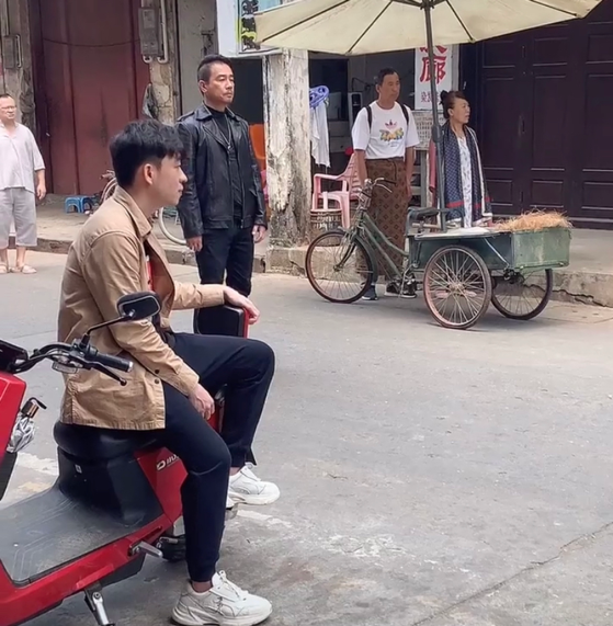 陈小春|陈小春在海南拍戏，大热天还穿着皮衣，寥寥几个路人坐电动车观望