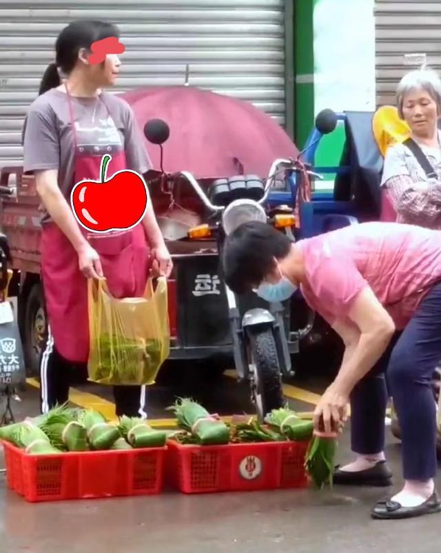 大妈手持粽子叶疯狂甩水,摊贩冷脸无奈等候,一旁大妈笑而不语