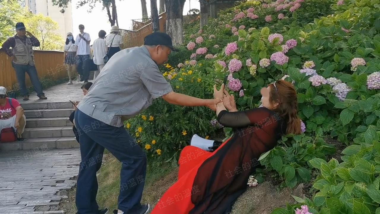 大妈赖在花丛中不肯走，保安大叔拉都拉不动，以为自己是杨贵妃？