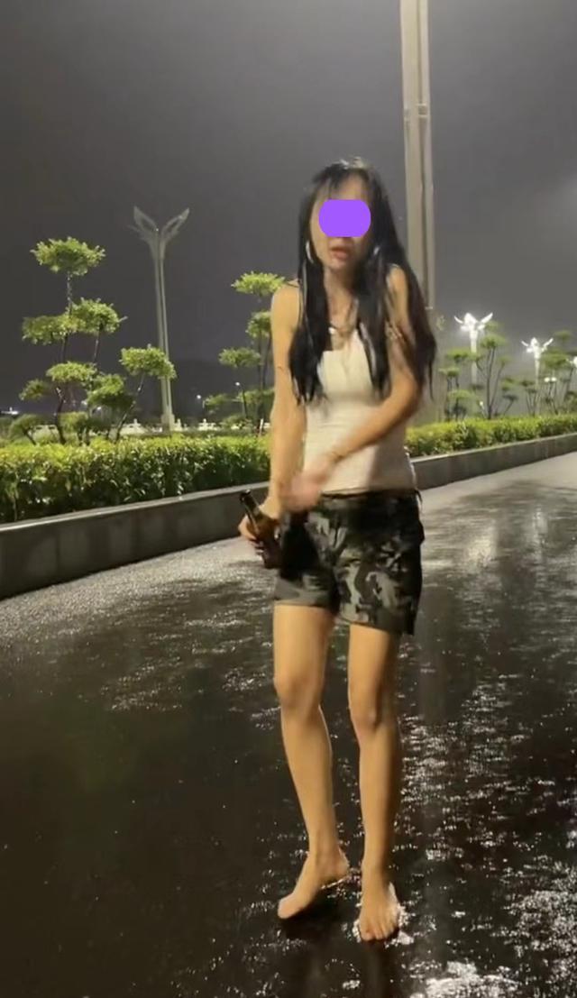 一女子为了缓解压力,光着脚丫走在马路上,手上还抓着一瓶啤酒