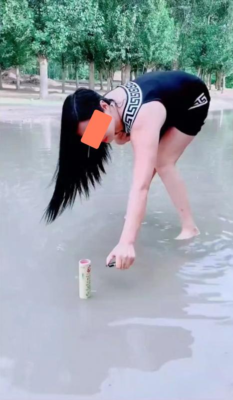 一女子在积水的路面上放鞭炮,鞭炮还没点着,自己就先被吓跑了