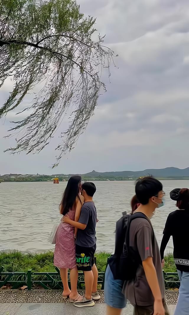 一男子在湖边,无视过往路人,和身高比自己高出半个头的女子相拥