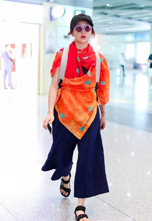 周迅的穿着让人摸不透，藏蓝色阔腿裤清爽潇洒，却配了件橘色披肩