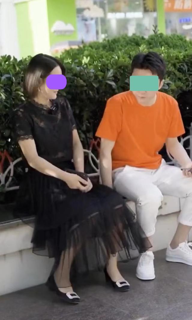 一女子去搭讪坐在路边玩手机的男子,男子害羞,不愿让她靠近