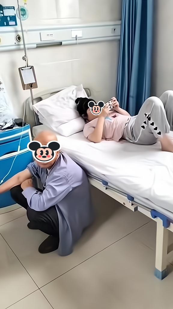 孙女将生病的爷爷挤下病床,自己躺在床上玩游戏,爷爷一脸无奈
