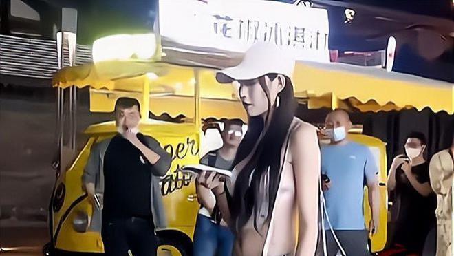 一名女子走出家门，一条热裤下的刺青清晰可见，引得路人纷纷围观拍照