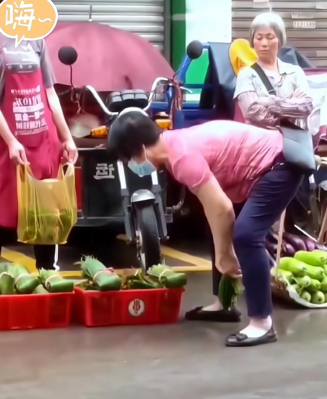 大妈手持粽子叶疯狂甩水,摊贩冷脸无奈等候,一旁大妈笑而不语