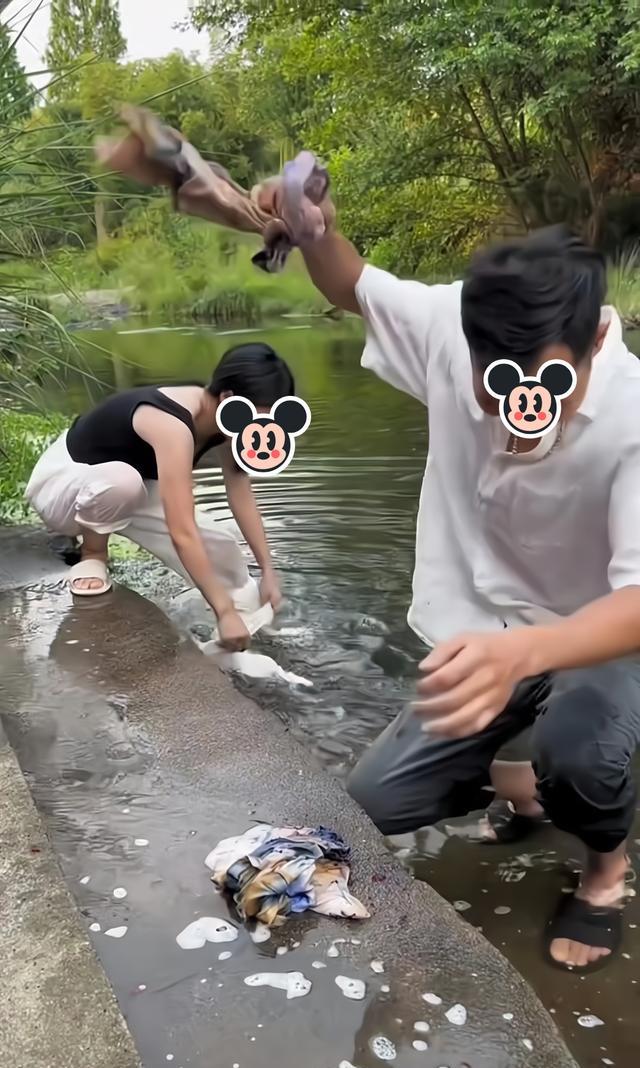 一男子没有耐心洗衣服并把衣服扔河里,在一旁的女子:姐教你洗