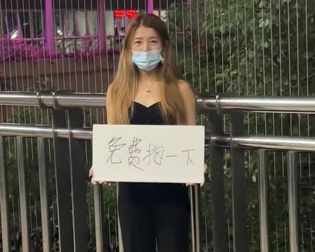 广东两女子夜晚站天桥边,举牌售卖拥抱,网友:收费的不一定好