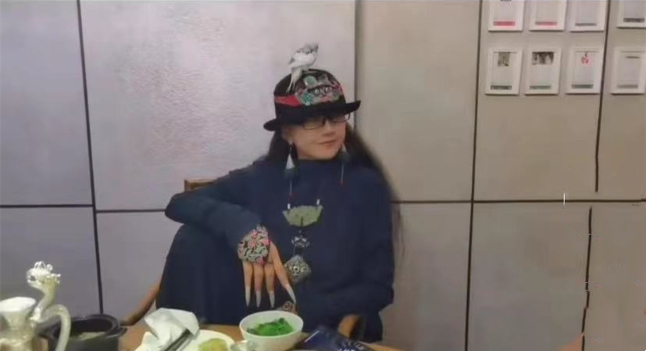 杨丽萍|63岁杨丽萍与友聚餐惹争议！脚踩座椅头顶小飞鸟，胸前大玉佩瞩目