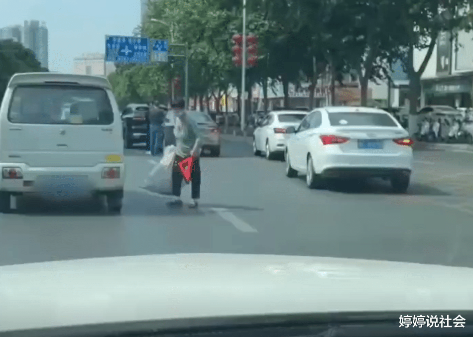 懵了!河南一交通事故正在协商中,大妈竟在车流中顺走警示三角架