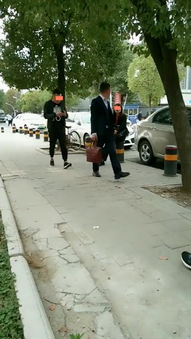 女子朝男子吹口哨,男子回头看却没停下前进的脚步,不慎撞树上