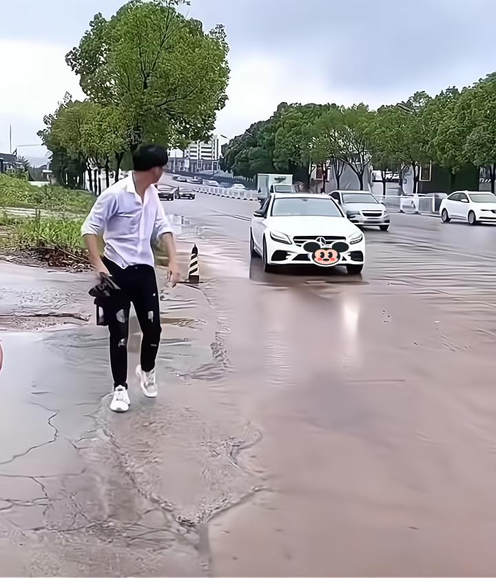 一男子见身后有车驶来,担心两名女子被雨水溅到,冲过去护住她们