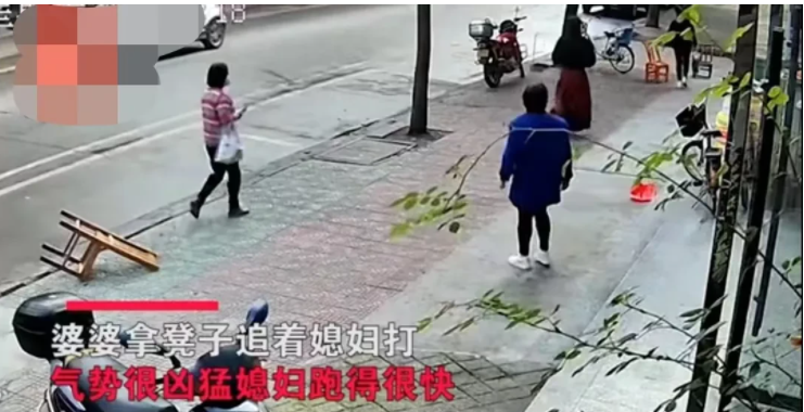 湖南。一位婆婆拿着凳子追打儿媳,女子飞快地跑出门