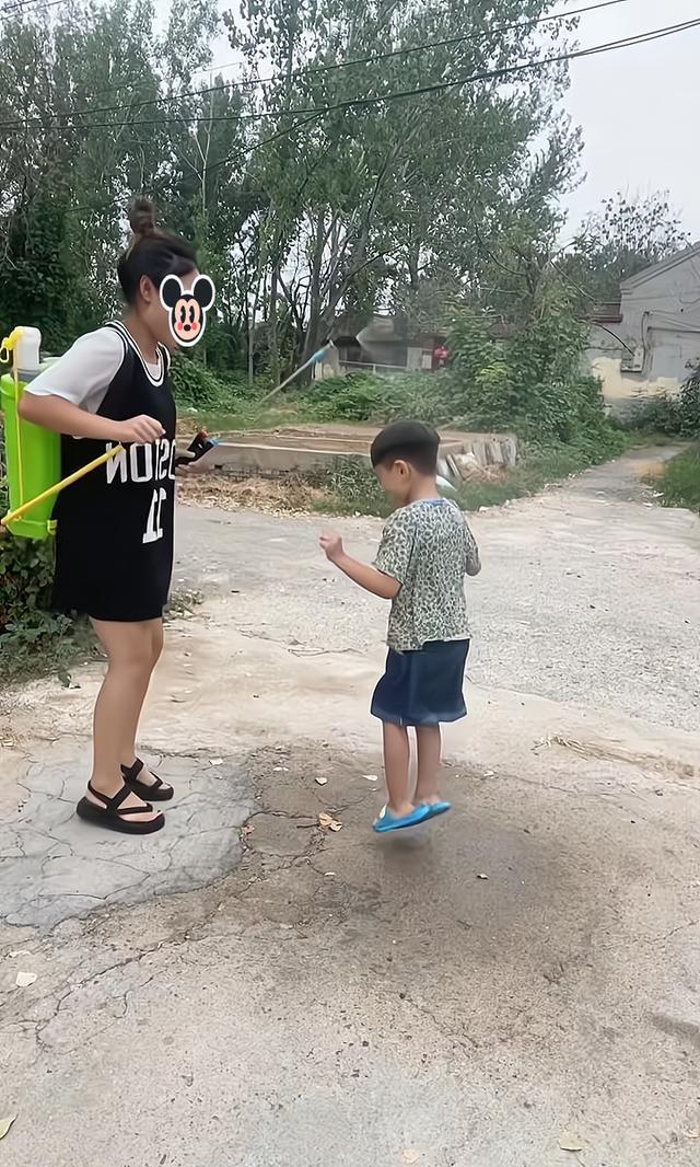 一女子拿喷雾器喷水给侄子玩耍,看到嫂子回来,她撒腿就跑
