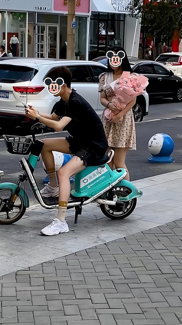 女子手捧鲜花,想向男子表白却害羞,路过的大姐把她推到男子怀里