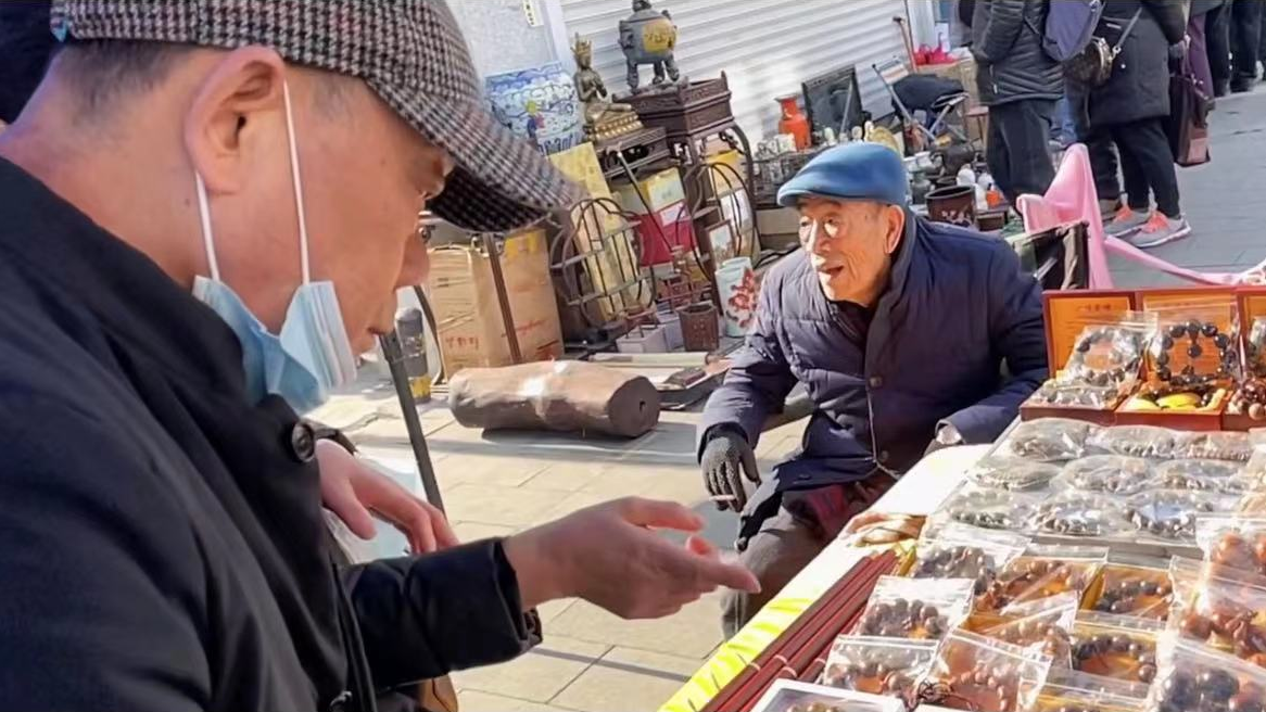 90岁杨少华在天津街头摆摊,坐轮椅穿厚袄清点货物,引众人围观