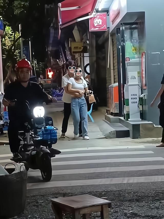 一男子担心喝醉酒的女友摔倒，抱着她走路，她却很不情愿